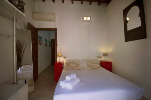 Un dormitorio con una cama blanca con toallas. en Ático Elvira, en Granada