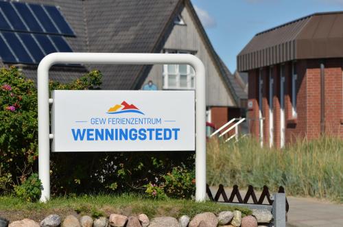 um sinal em frente a uma casa com um edifício em Ferienzentrum Wenningstedt em Wenningstedt