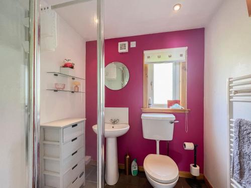 a pink bathroom with a toilet and a sink at Cuillin Cottage in Arnisdale