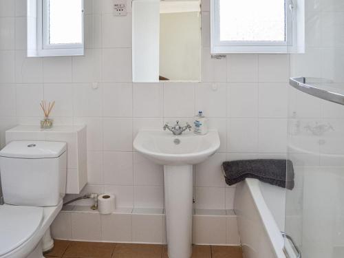 a white bathroom with a sink and a toilet at Bermuda Haven in Hemsby