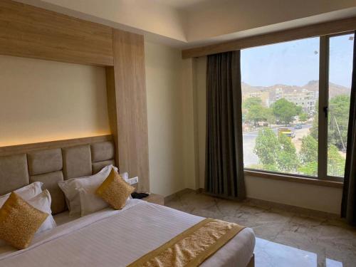 een hotelkamer met een bed en een groot raam bij Hotel Lilichham in Udaipur