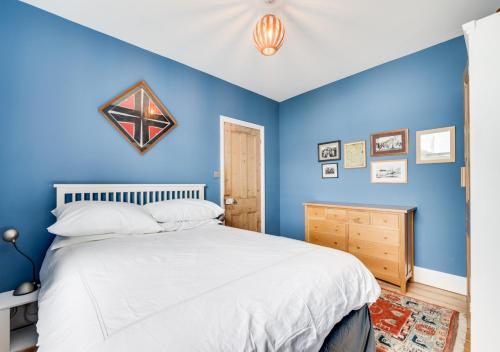 West Hill Cottage في برايتون أند هوف: غرفة نوم زرقاء مع سرير وجدار ازرق