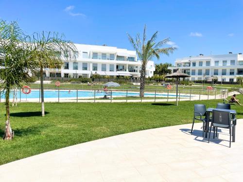 a table and chairs in a park with a pool at Apartamento en Costa Ballena in Chipiona