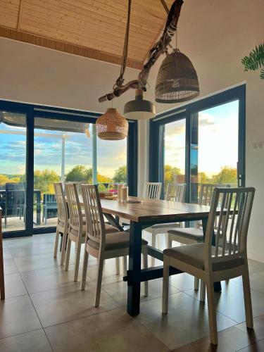 a dining room with a table and chairs and windows at Houses with a View#Sauna#Jaccuzi in Gozdowice