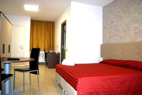 a hotel room with a red bed and a table at Piazza Dante in Taranto