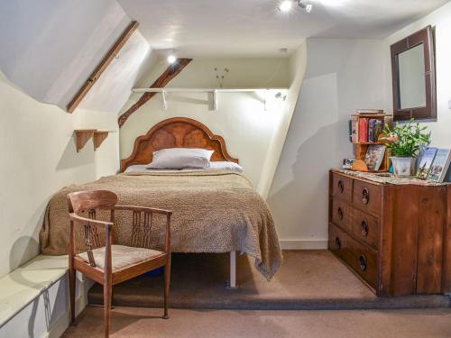 a bedroom with a bed and a chair and a dresser at Hoopers Farmhouse in Tilshead