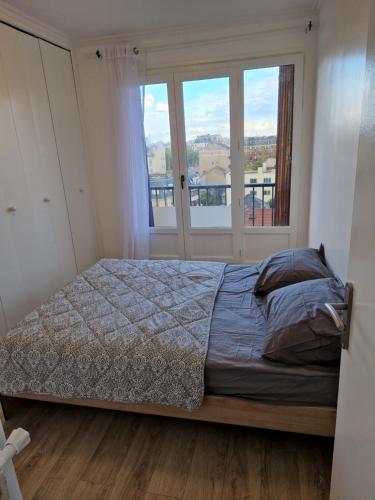 a bedroom with a bed and a window at Appartement spacieux rénové - 11 min de Paris in Colombes