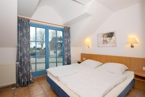 a bedroom with a bed and a large window at Ferienresidenz Kap Arkona FeWo 06 - Balkon, OG und DG in Putgarten