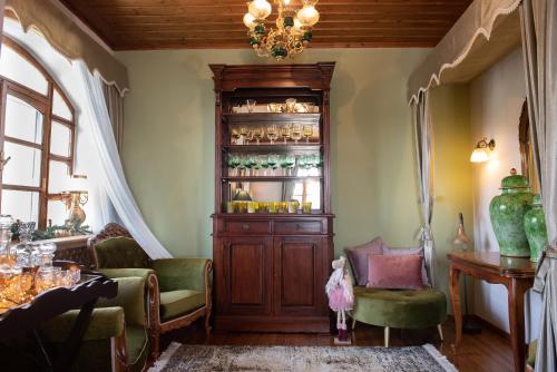a living room with a chandelier and green chairs at Dandy Villas Nymfaio - Snow Fairy - Sauna in Nimfaíon
