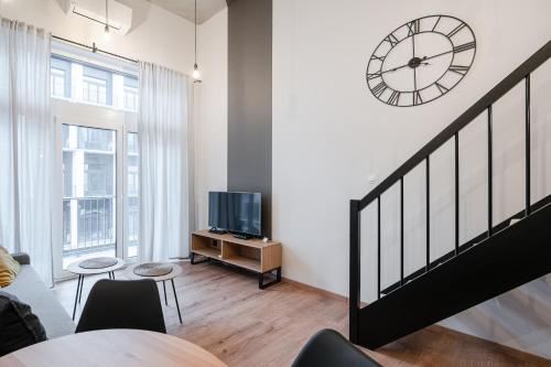 a living room with a staircase and a clock on the wall at RentPlanet - Apartamenty Zarembowicza in Wrocław
