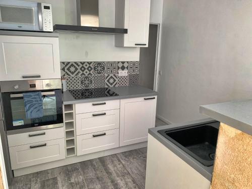 a kitchen with white cabinets and a microwave at The Loft Factory 4 Chambres Vue Garonne + Jardin in Lormont