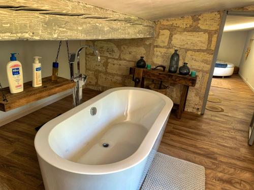 a white bath tub in a bathroom with wooden floors at The Loft Factory 4 Chambres Vue Garonne + Jardin in Lormont