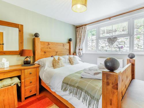 a bedroom with a bed and a desk and a window at Elsies Cottage in Pontesbury