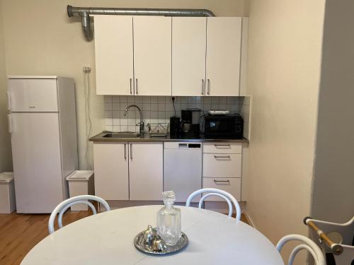 a kitchen with a white table and a white refrigerator at Rut & Ragnars Vandrarhem in Malmö