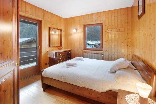 a bedroom with a bed and a wooden wall at Mountain Chalet close to Bormio in Valdisotto