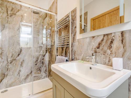 a bathroom with a sink and a shower at Penshenkin Barn in Llanfihangel-nant-Melan