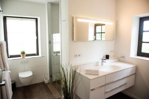 a white bathroom with a sink and a mirror at Seehof direkt am See mit privatem Seezugang 