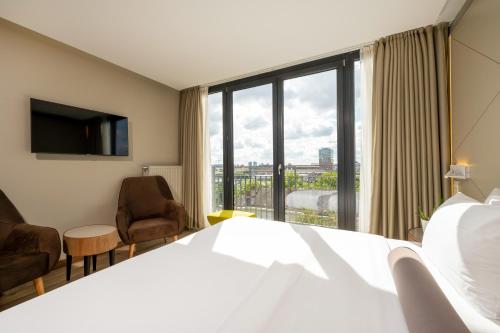 ein Hotelzimmer mit einem Bett und einem großen Fenster in der Unterkunft Hotel Klassik Berlin in Berlin