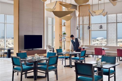 a man standing in a restaurant with tables and chairs at Crowne Plaza - Jeddah Al Salam by IHG in Jeddah