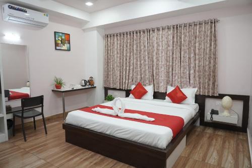 a bedroom with a bed with red pillows and a desk at Hotel Silver Cloud in Jodhpur