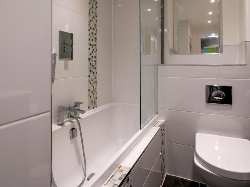 een witte badkamer met een douche en een wastafel bij Pass the Keys Delightful 4 bedroom Cotswold character cottage in Cheltenham