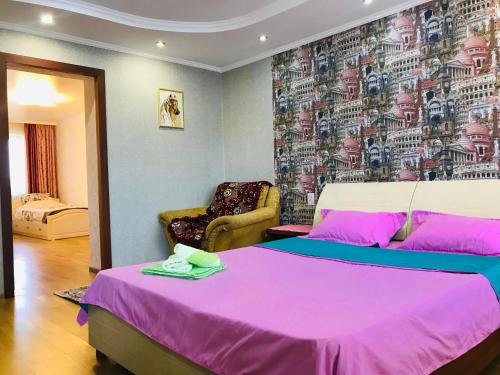 a bedroom with a large pink bed and a chair at Apartments in the city center in Karagandy