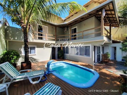 ボンビーニャスにあるCasa Naviti Rua Bem Te Vi 233 Bombinhas com piscinaの椅子2脚と家があるデッキのプール