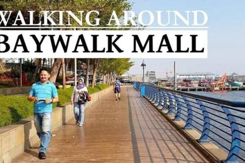 a walkway near the water with people walking around baywalk mall at Sailor Studio Fast Wifi Android TV at Apt Green Bay Pluit Tower F in Jakarta