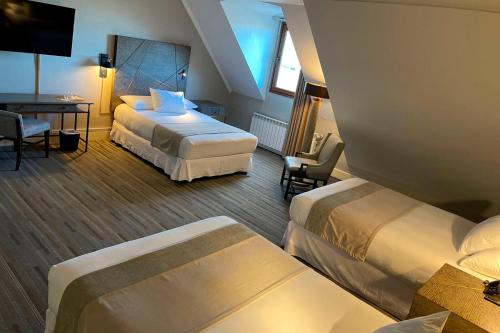 a hotel room with two beds and a table at Hotel Cabo De Hornos in Punta Arenas