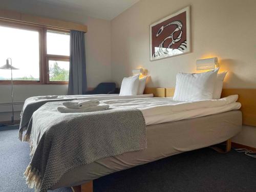 una habitación de hotel con una cama grande con sábanas blancas en Vålådalens Fjällstation, en Vålådalen
