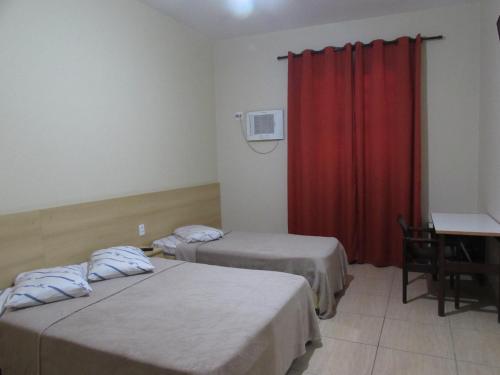 Cette chambre comprend 2 lits et un rideau rouge. dans l'établissement Nébias Palace Hotel junto da Avenida Ipiranga com São João em Frente ao Bar Brahma SP, à São Paulo
