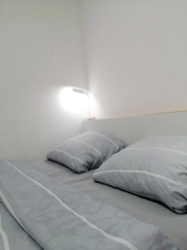 a bed with two pillows and a lamp on the wall at NIKAS Apartman in Donji Milanovac