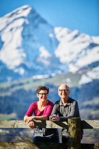 a man and woman sitting on a bench in front of a mountain at Landhus Almens in Almens