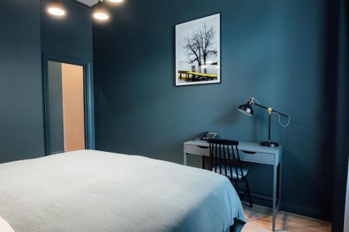 a blue bedroom with a bed and a desk at Aparthotel Amella in Rīga