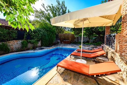 a pool with two chairs and an umbrella at Sarnıç - Kayaköy'de Havuzu Korunaklı in Kayakoy