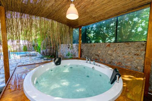 a large bath tub in a room with a large window at Sarnıç - Kayaköy'de Havuzu Korunaklı in Kayakoy