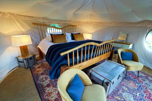ein Schlafzimmer mit einem Bett und einem Stuhl in einem Zelt in der Unterkunft Horsley Hale Farm Glamping in Ely