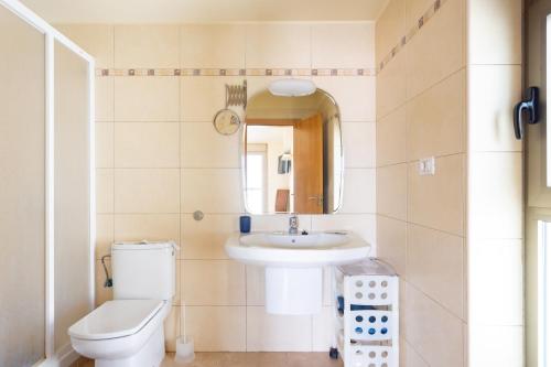 a bathroom with a sink and a toilet and a mirror at 121 MEDANO Perfect Stay By Sunkeyrents in El Médano