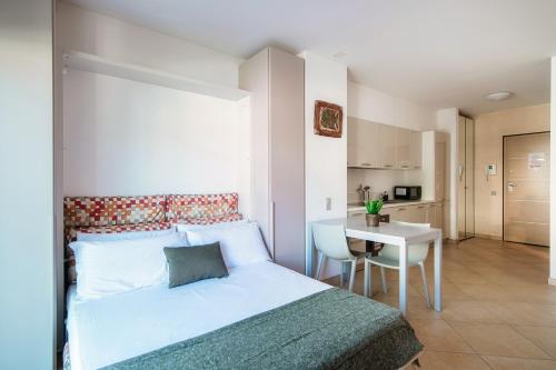 a bedroom with a bed and a table and a kitchen at Prestige 7 by Quokka 360 - quiet studio with balcony in Lugano