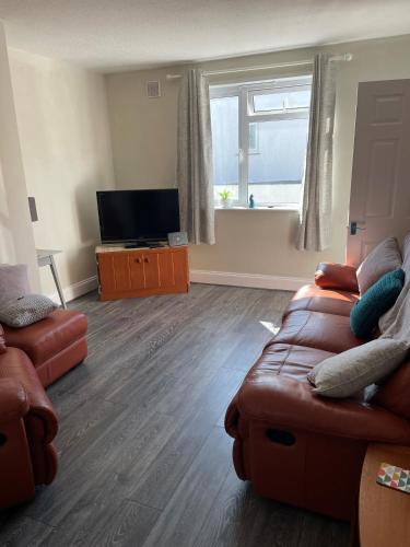 a living room with a couch and a flat screen tv at Cheerful - 2 bedroom home in St Ives. in St Ives