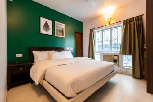 een slaapkamer met een groot bed met een groene muur bij HANDMADE HOMES HAZRA: 2 BED APARTMENT AT KALIGHAT in Calcutta