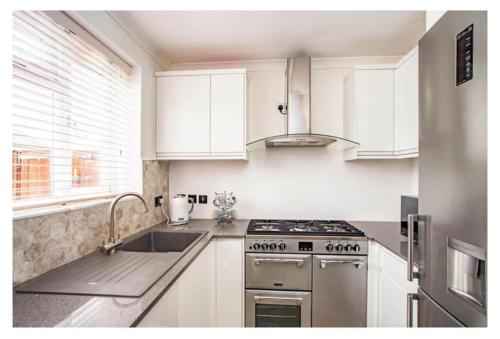 uma cozinha com armários brancos e um forno com placa de fogão em 2 Bed - walking distance to Harry Potter Studio em Leavesden Green