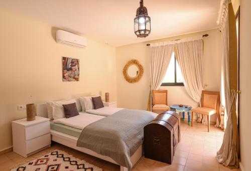 um quarto com uma cama, uma cadeira e uma janela em Tiguemine Sarah em Marraquexe