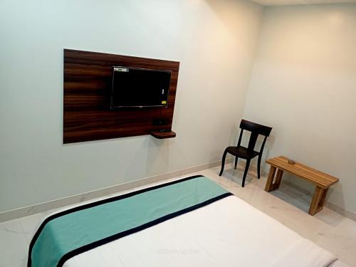 a room with a bed and a tv and a chair at VIAN INN in Guwahati