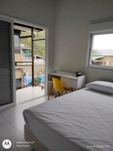 a bedroom with a bed and a desk and a balcony at FRANCIS HOTEL MAR in Caraguatatuba