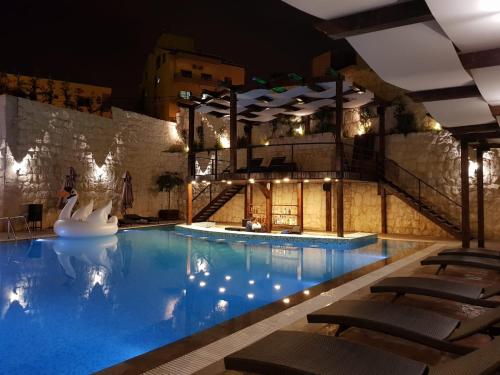 a swimming pool at night with chairs and lights at Ibiza Hotel in Jounieh
