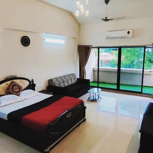 a bedroom with a bed and a couch and windows at Kappys Villa in Igatpuri