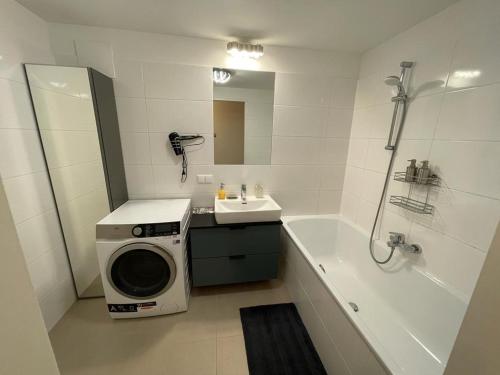 a bathroom with a washing machine next to a bath tub at Lovely 3 rooms apartment viena in Vienna