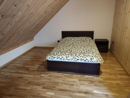 een slaapkamer met een bed en een houten vloer bij Apartamentai Pušyne in Druskininkai