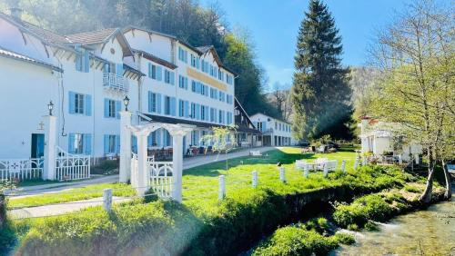 a large white building next to a river at Les Contes in Fougax-et-Barrineuf